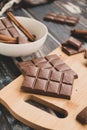 Milk dark chocolate tiles on wood cutting board, wooden background Royalty Free Stock Photo