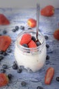 Milk dessert close-up with vignette. Yogurt in a jar, with strawberries and blueberries. Useful breakfast. Royalty Free Stock Photo