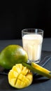 Milk drink on black background with mango. A classic mango milkshake - Lassi. A traditional drink in India from the heat