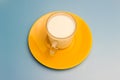Milk in a glass cup on a yellow saucer Royalty Free Stock Photo