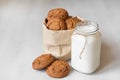 Milk in a glass jar and oatmeal cookies in a paper bag on a white table background. Copy, empty space for text Royalty Free Stock Photo