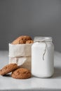 Milk in a glass jar and oatmeal cookies in a paper bag on a white table background. Copy, empty space for text Royalty Free Stock Photo