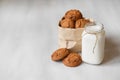 Milk in a glass jar and oatmeal cookies in a paper bag on a white table background. Copy, empty space for text Royalty Free Stock Photo