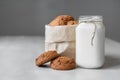 Milk in a glass jar and oatmeal cookies in a paper bag on a white table background. Copy, empty space for text Royalty Free Stock Photo