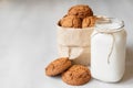 Milk in a glass jar and oatmeal cookies in a paper bag on a white table background. Copy, empty space for text Royalty Free Stock Photo