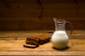 Milk from a glass jug poured into a glass, a loaf of rye bread, ears Royalty Free Stock Photo