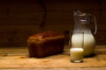 Milk from a glass jug poured into a glass, a loaf of rye bread, ears Royalty Free Stock Photo