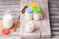 Milk jars with colorful caps on a cutting board, cinnamon and drinking straw