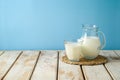 Milk jug and milk glass on wooden table over blue background. Kitchen mock up for design Royalty Free Stock Photo