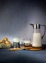Milk from a jug pouring into glass, muffins on old wooden table. space for text Royalty Free Stock Photo