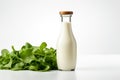 Milk, kefir or salad dressing in a bottle on a white background with fresh green salad