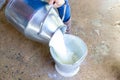 Milk pouring from a milk bottle into a metal bucket Royalty Free Stock Photo