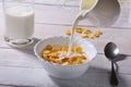 Milk pouring into a bowl of delicious corn flake cereals and cap with espresso coffee. Morning breakfast. Royalty Free Stock Photo