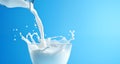 Milk pouring into glass bowl on blue background with copy space Royalty Free Stock Photo