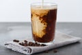 Milk pouring into ice coffee in glass on napkin with coffee grains isolated on white. Royalty Free Stock Photo