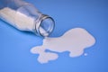 Milk is pouring out of a bottle. Spent milk on a blue background. Royalty Free Stock Photo