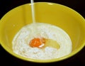 Milk pouring into yellow ceramic mixing bowl on dry flour and egg yolk Royalty Free Stock Photo