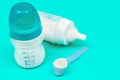 Milk powder for baby in measuring spoon near baby bottles on mint background Royalty Free Stock Photo