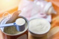 Milk powder in spoon with can and baby bottle milk in bowl on wooden table Royalty Free Stock Photo