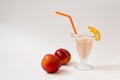 Milk refreshing cocktail with nectarine in a beautiful figured glass with an orange tube and a piece of fruit on the glass, two ma Royalty Free Stock Photo