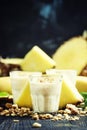 Milk smoothies with banana, pineapple and granola, dark background, selective focus