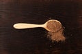 Milk Thistle powder or Silybum marianum extract in wooden spoon on brown wooden background. Herbal superfood for aiding liver