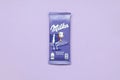 Milka chocolate tablet in classic violet wrapping on lilac background. Milka is brand of chocolate confection originated in Royalty Free Stock Photo