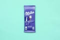 Milka chocolate tablet in classic violet wrapping on pastel blue background. Milka is brand of chocolate confection originated in Royalty Free Stock Photo