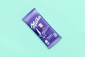 Milka chocolate tablet in classic violet wrapping on pastel blue background. Milka is brand of chocolate confection originated in Royalty Free Stock Photo