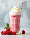 Milkshake cocktail in tall glass on concrete surface, topped with berries raspberries, whipped cream and straw