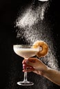 Milkshake glass and donut on black background. Powdered sugar falls