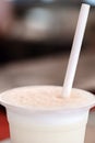 milkshake in plastic cup with straw, close-up, selective focus