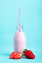 Milkshake with strawberries or drinking yogurt in a bottle with a beautiful straw with ripe strawberries and strawberry slices on