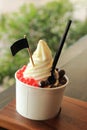 Milky ice cream soft serve in paper cup topping with chocolate ball and red jelly Royalty Free Stock Photo