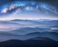 Milky Way arch over the mountains in fog at starry night Royalty Free Stock Photo