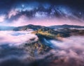 Milky Way arch over the mountains in low clouds at starry night Royalty Free Stock Photo