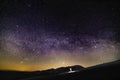 Beautiful night sky with stars and silhouette of a standing alone man on the mountain Royalty Free Stock Photo