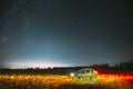 Milky Way Galaxy In Night Starry Sky With Glowing Stars Above Green Renault Duster SUV In Countryside Landscape. Milky