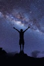 Silhouette of Happy man standing on top of mountain with night sky and bright star on background.