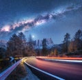 Milky Way over mountain road. Blurred car headlights