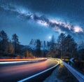 Milky Way over mountain road. Blurred car headlights