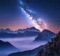 Milky Way over mountains in fog at night in summer