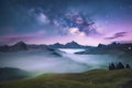 Milky Way over mountains in fog at night in summer. Landscape with foggy alpine mountain valley Royalty Free Stock Photo