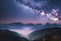 Milky Way over mountains in fog at night in summer. Landscape with foggy alpine mountain valley Royalty Free Stock Photo