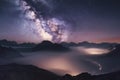 Milky Way over mountains in fog at night in summer. Landscape with foggy alpine mountain valley Royalty Free Stock Photo