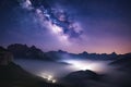 Milky Way over mountains in fog at night in summer. Landscape with foggy alpine mountain valley Royalty Free Stock Photo
