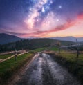 Milky Way over the rural road, wooden fence in mountains at night Royalty Free Stock Photo