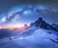 Milky Way over snowy mountains and car headlights on the road Royalty Free Stock Photo
