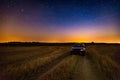 Milky way over stubble field, car and rural sandy road