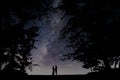 Milky Way with people under frame of tree . Landscape with night starry sky and silhouette of standing happy man and woman couple Royalty Free Stock Photo